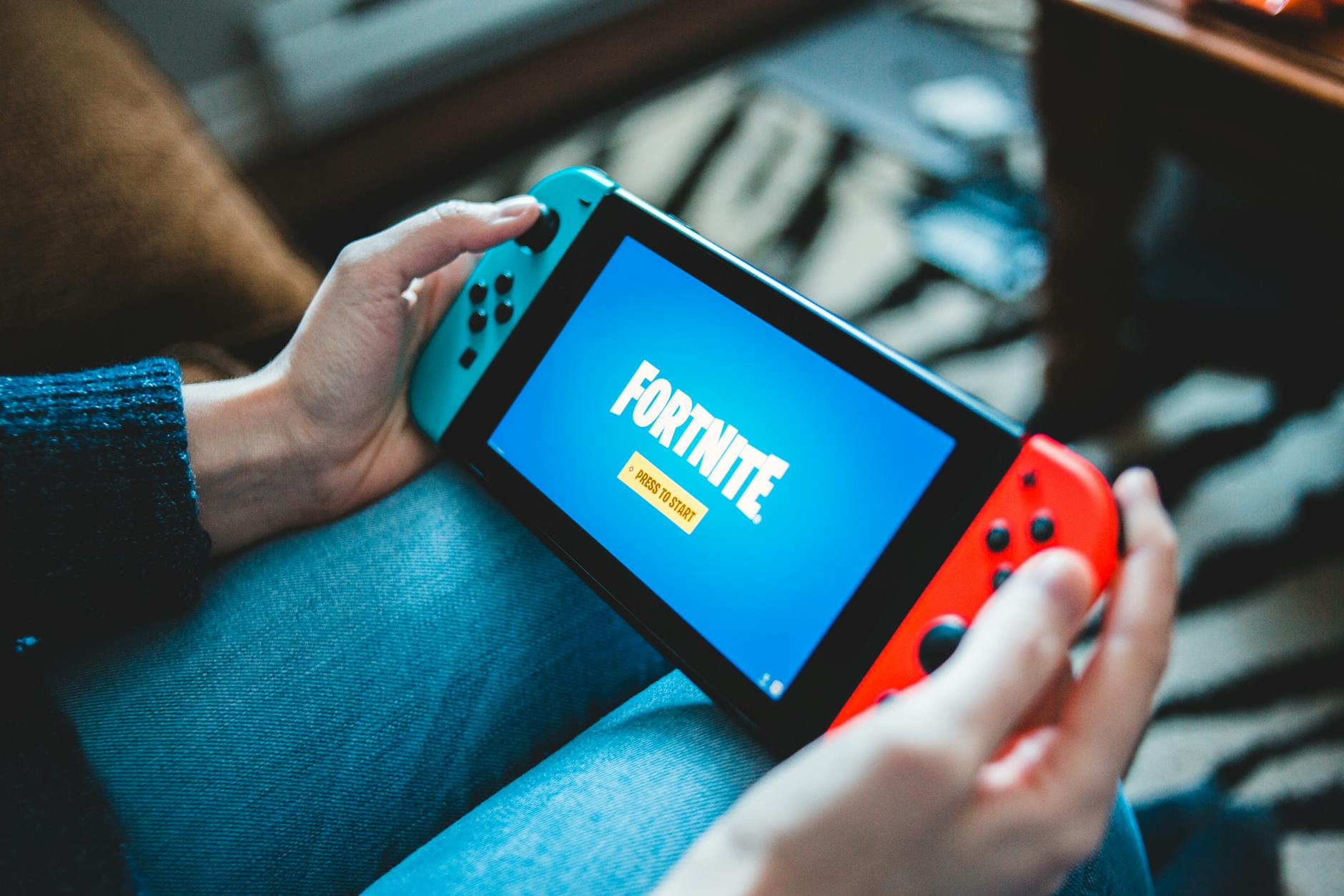 Dłonie trzymające Nintendo Switch z grą wideo na ekranie