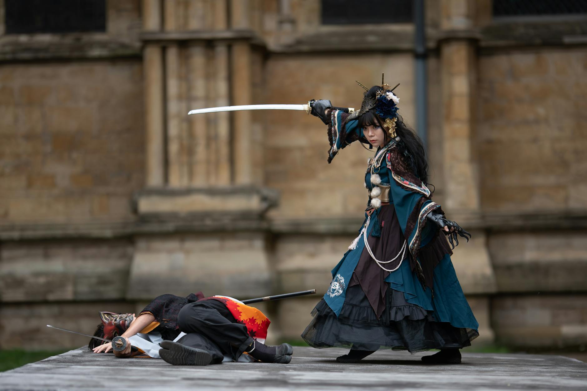 Dwóch cosplayerów walczy mieczami w dynamicznej scenie na zewnątrz