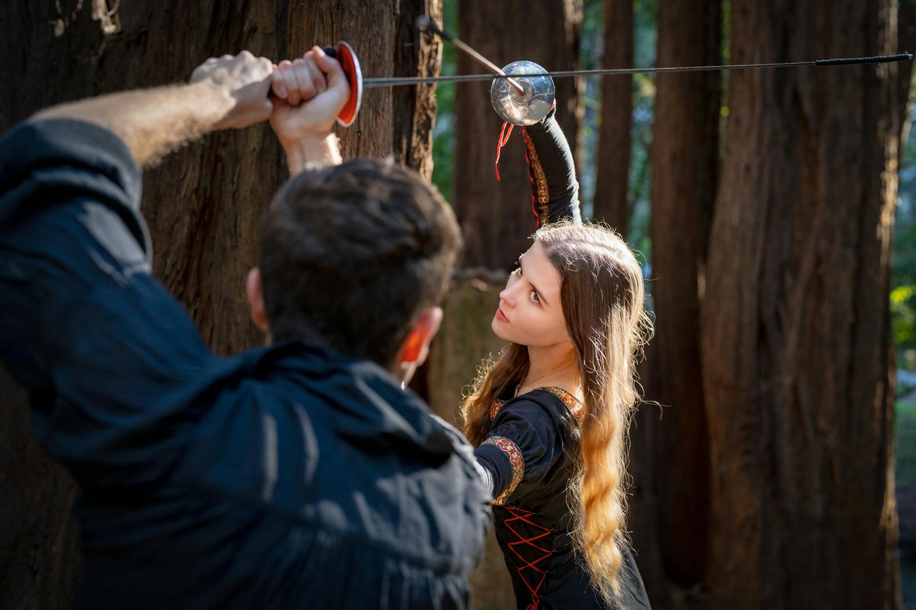 Mężczyzna i kobieta walczą na miecze w lesie jak w SoulCalibur II