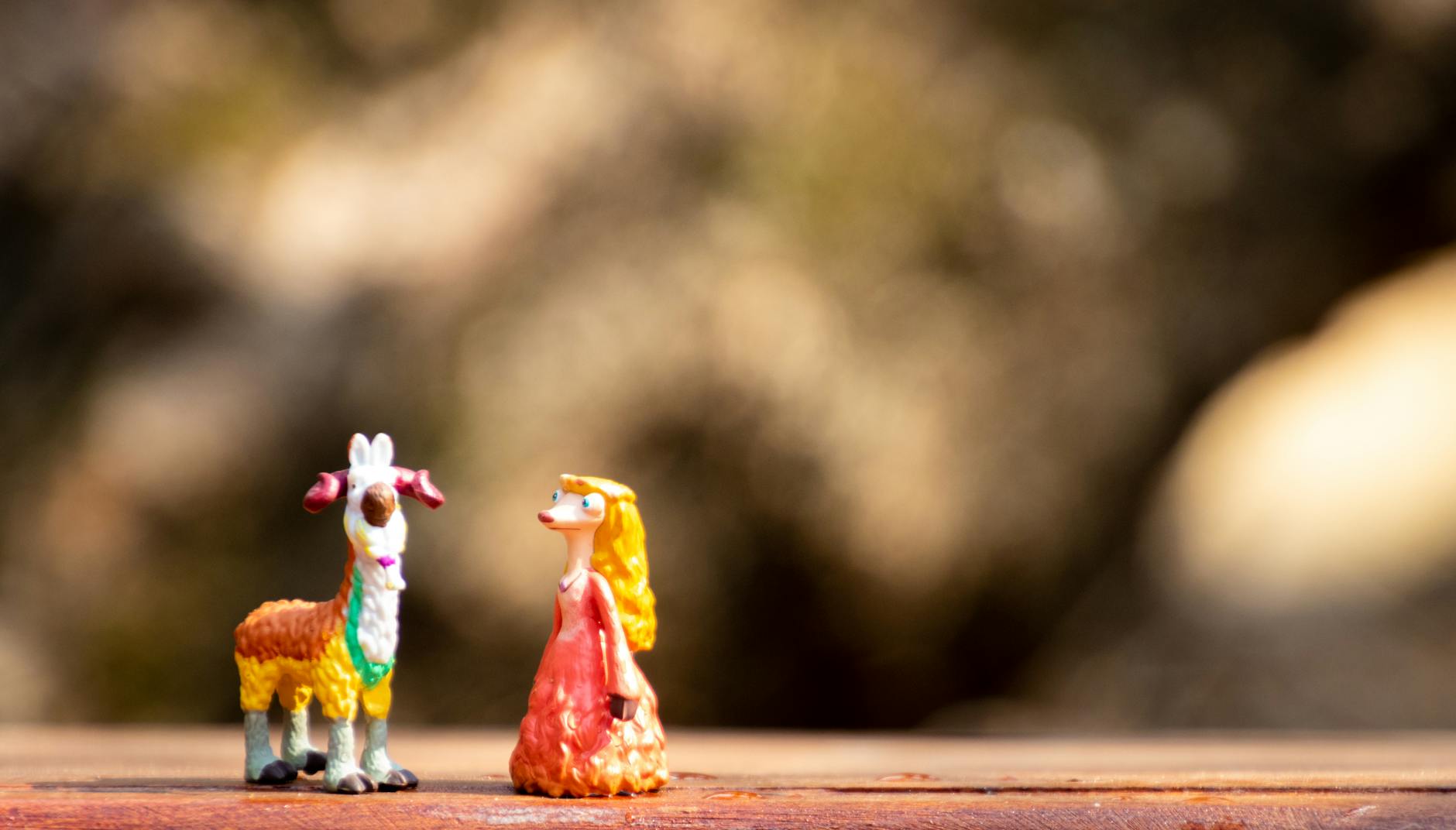 Figurki postaci i małej kozy na drewnianej, rustykalnej powierzchni