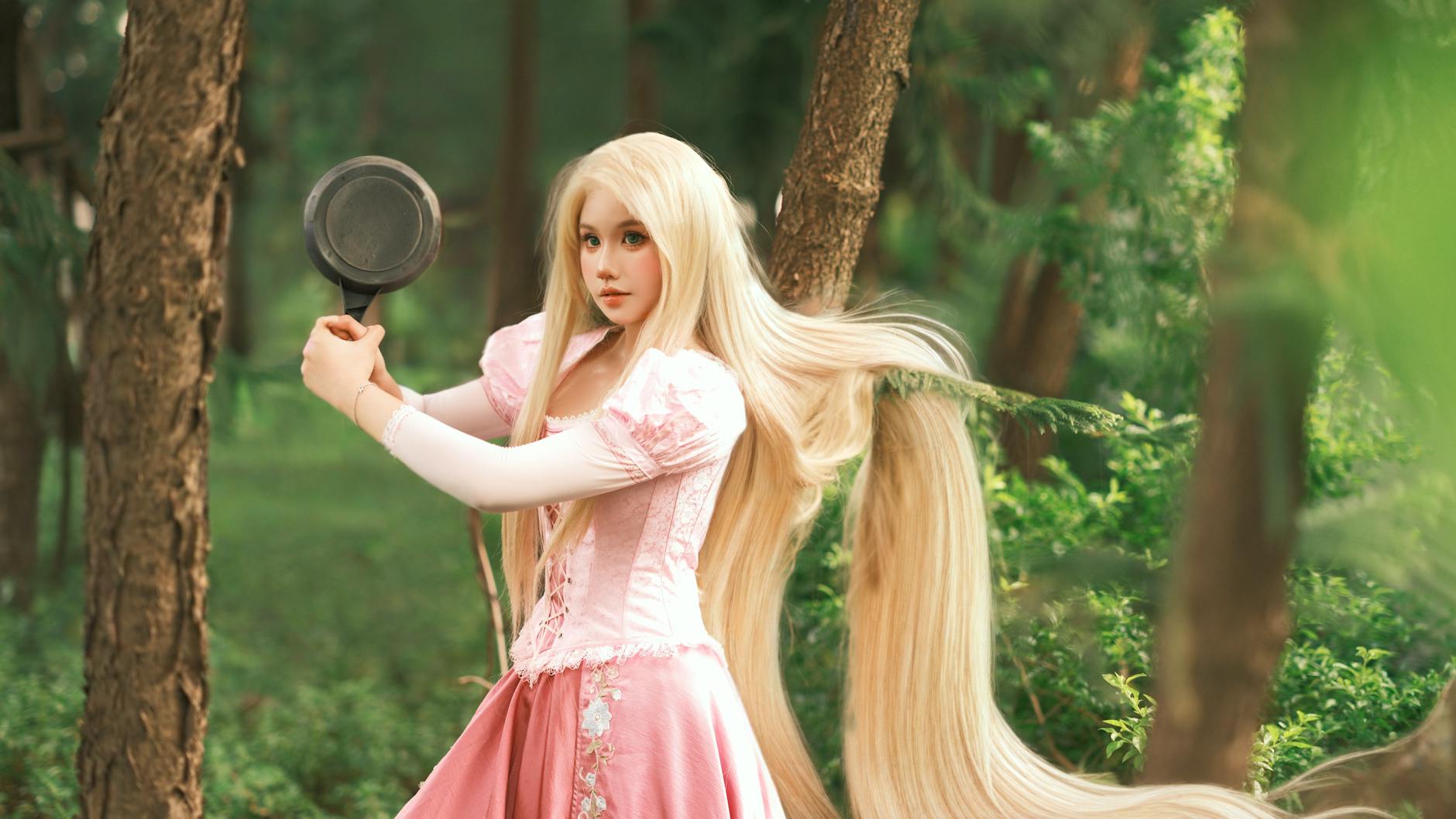 Kobieta przebrana za Lily z Blossom Tales w lesie, trzyma patelnię