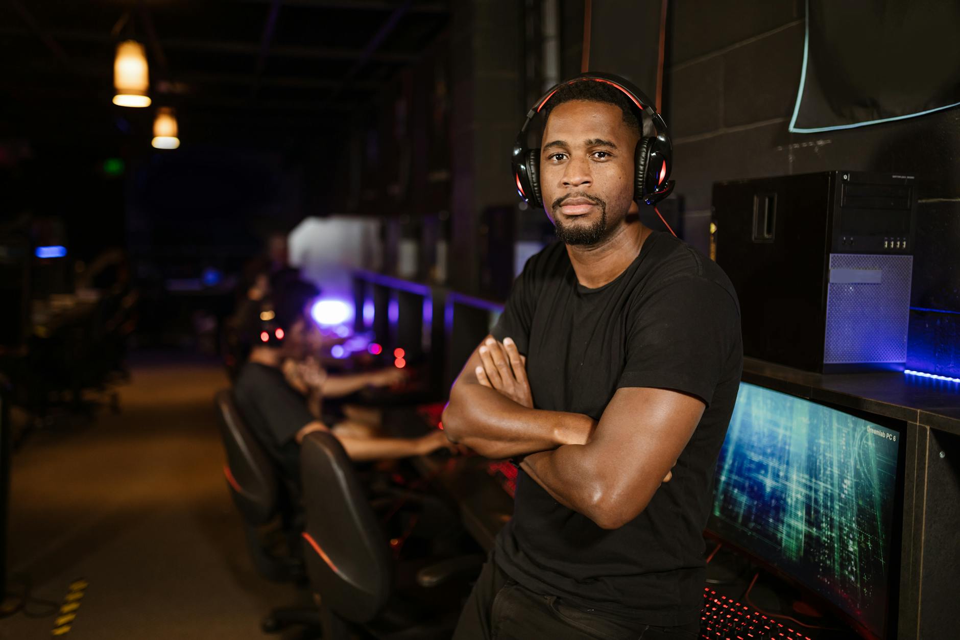 Młody gracz w słuchawkach skupiony przy komputerze na arenie e-sportowej