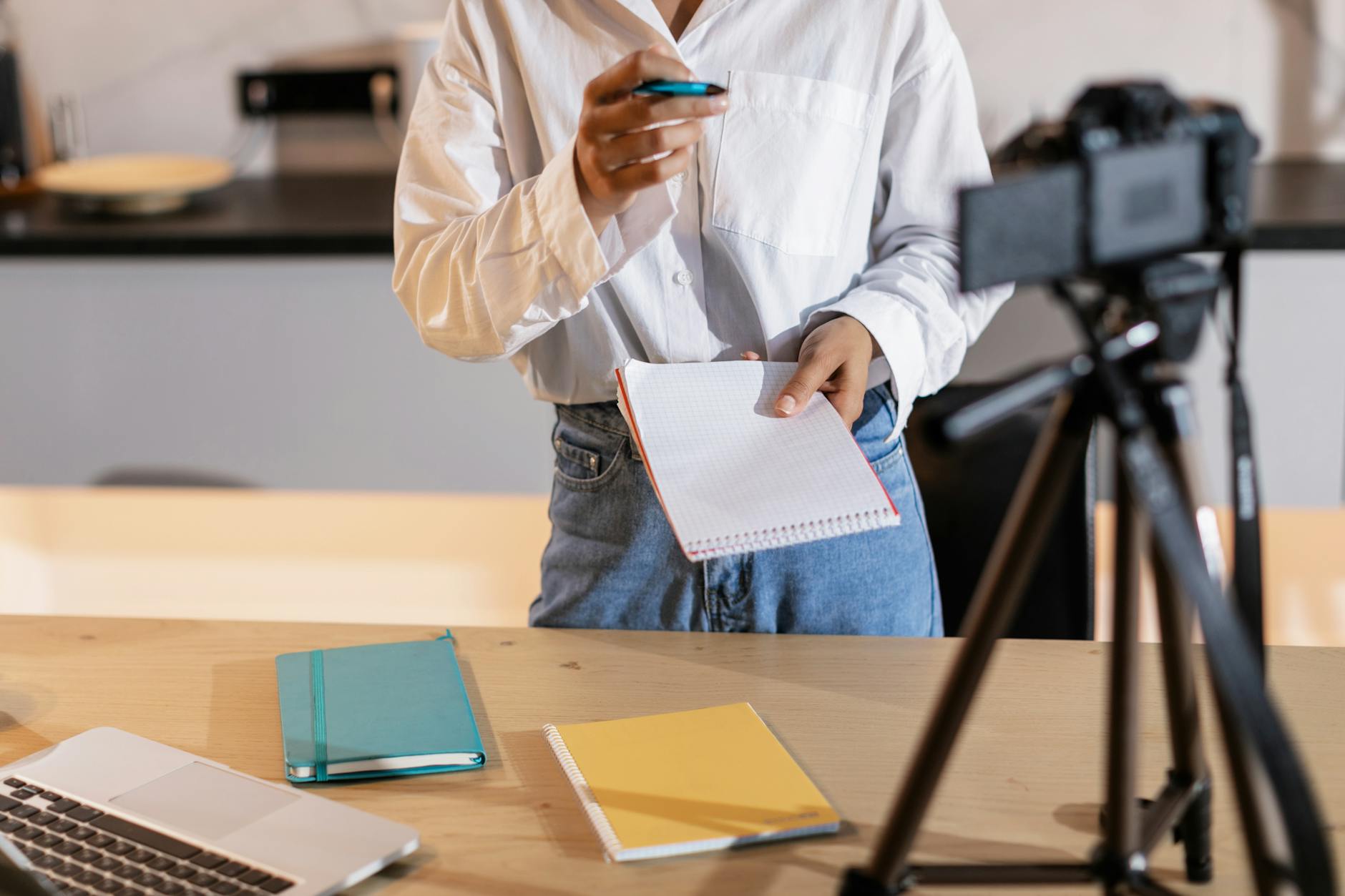 Vloger nagrywający treść, z notatkami i laptopem w nowoczesnym wnętrzu
